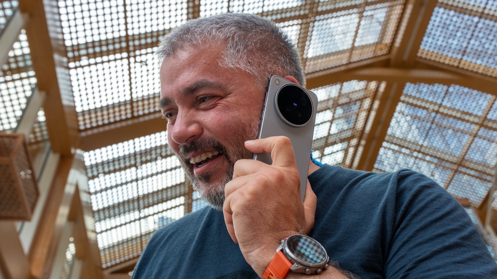 vivo X500 Pro Max přiložený k uchu při telefonování, s viditelným velkým kruhovým modulem fotoaparátů ZEISS.